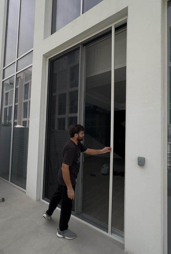 Installer fitting commercial mosquito screens at a Dubai premises