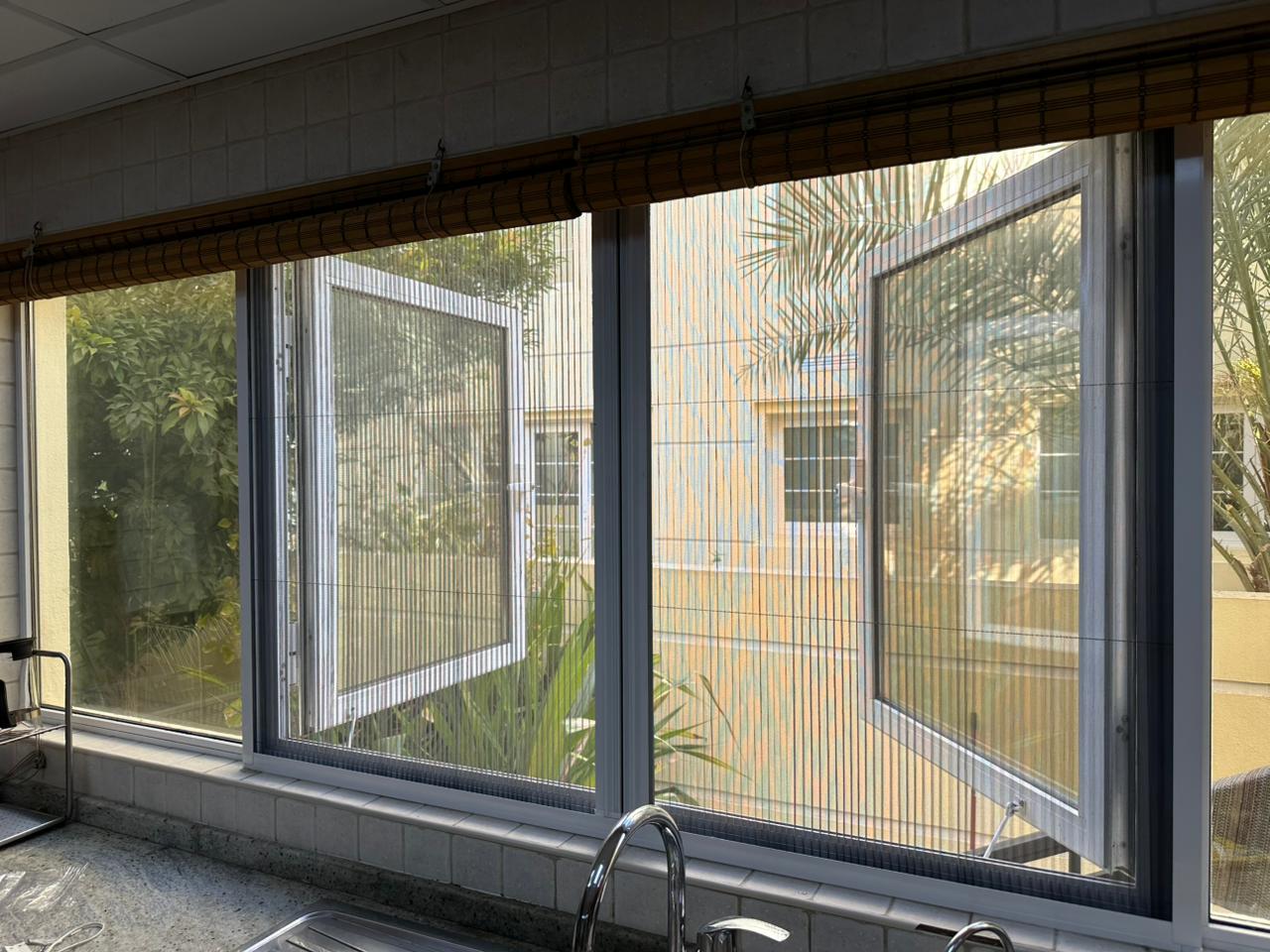 Fixed mosquito screens fitted to casement kitchen windows in Dubai villa with garden view